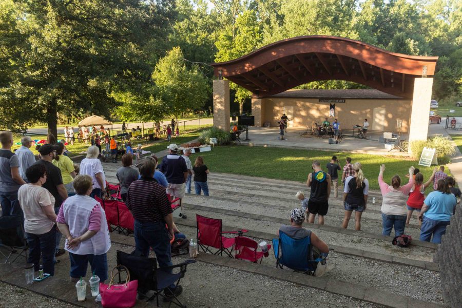 Audience members stand and sing as The Vineyard Churchs worship band leads the park in worship songs on Saturday during the Unity Rally at the Daum Amphitheater at Kiwanis Park. 