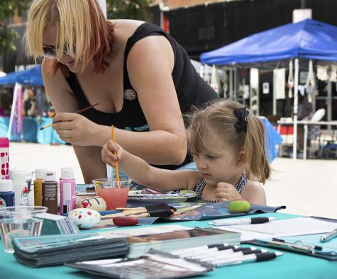 Nikky Davidson, a graduate student in the school of psychology, and her daughter Roxy, paint rocks Saturday morning at Muse Fest in the Charleston Square. 