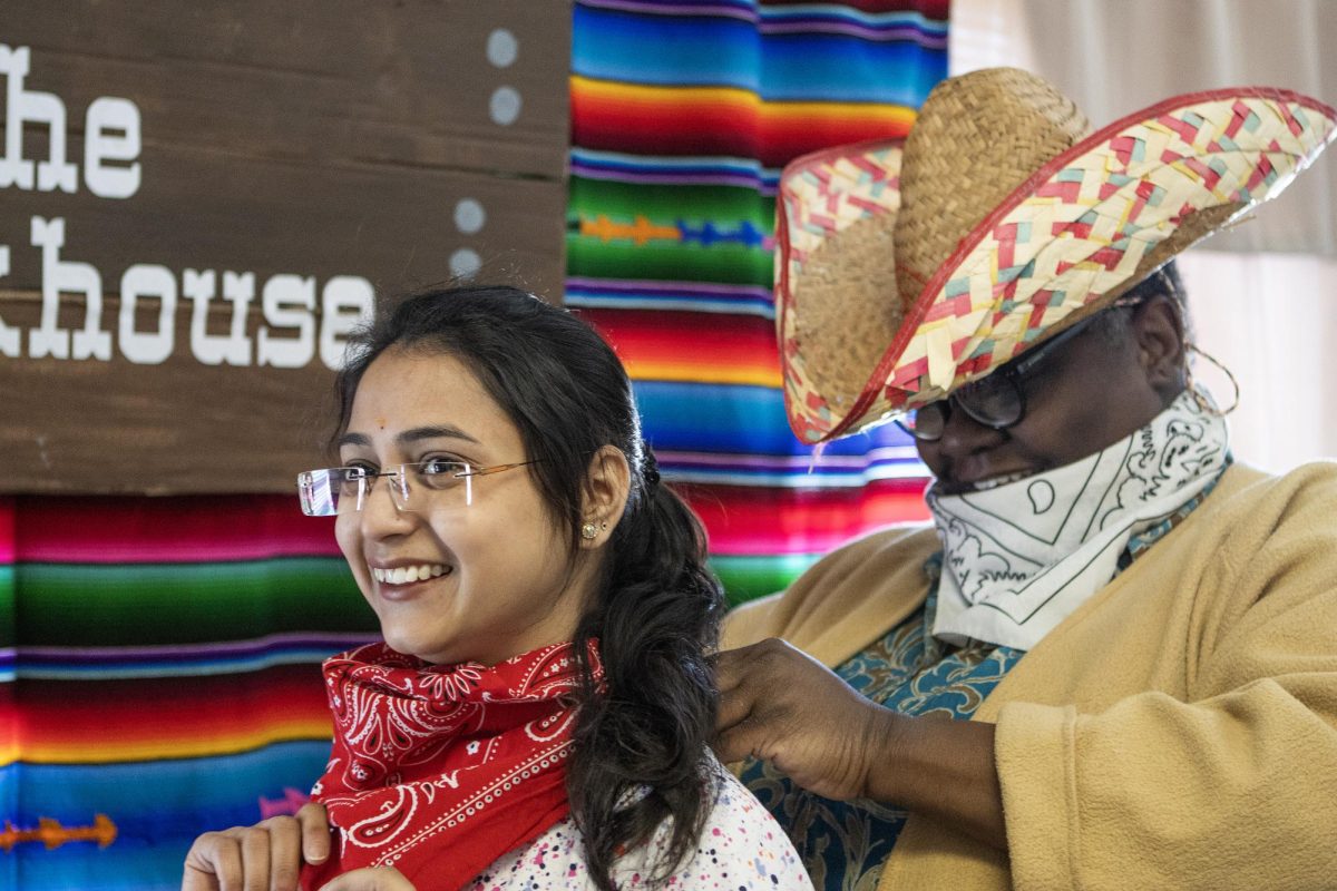 Marschelle McCoy helps Devika Jaiswal, a biological sciences graduate student, put on her handkerchief for the United Pentecostal Tabernacle churchs western themed lunch event on April 6.