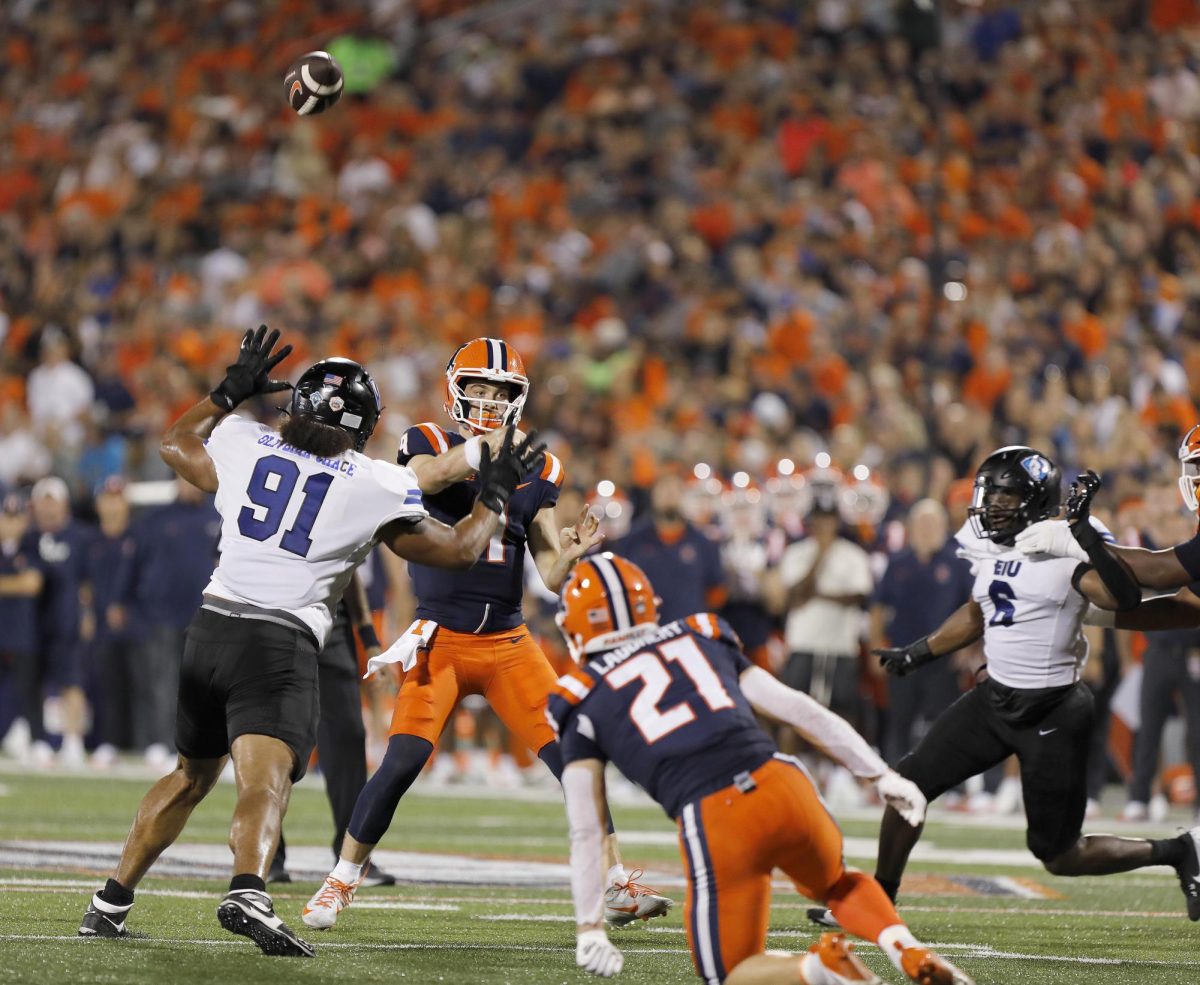 Illinois junior quarterback Luke Altmyer successfully throws the ball past  Eastern Illinois University's senior defensive lineman Jaron Hacha during the team's season opener against the Fighting Illini at Memorial Stadium Thursday night.