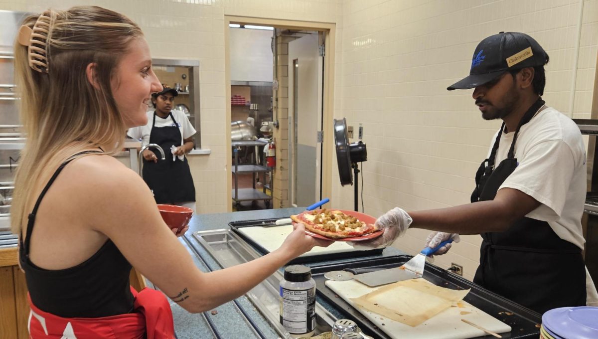 Sophomore criminal justice major Andrea Mattingly takes a plate of pizza from second year master's student in computer technology Chakravarthi Nukala in the South Quad dining Hall, 