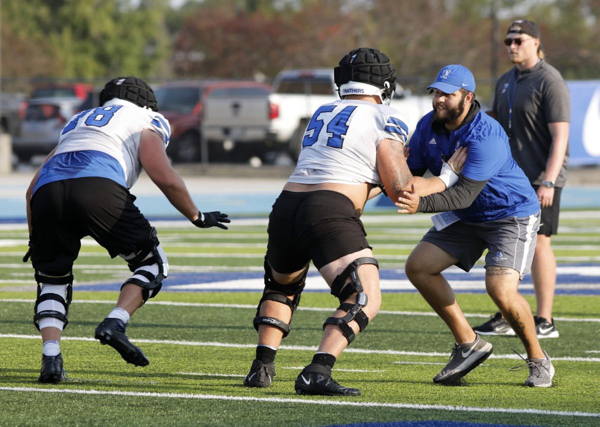 Tight ends coach Cole Hoover practices blocking players during football practice drills at O'Brien Field Wednesday afternoon.