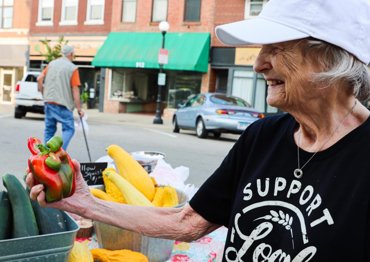 Bev Sterling holds an odd red pepper that makes her smile, in front of the courthouse. 