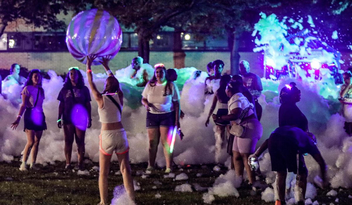 Students throw a glow in the dark ball around in the foam during the Glow Foam Party on the South Quad.