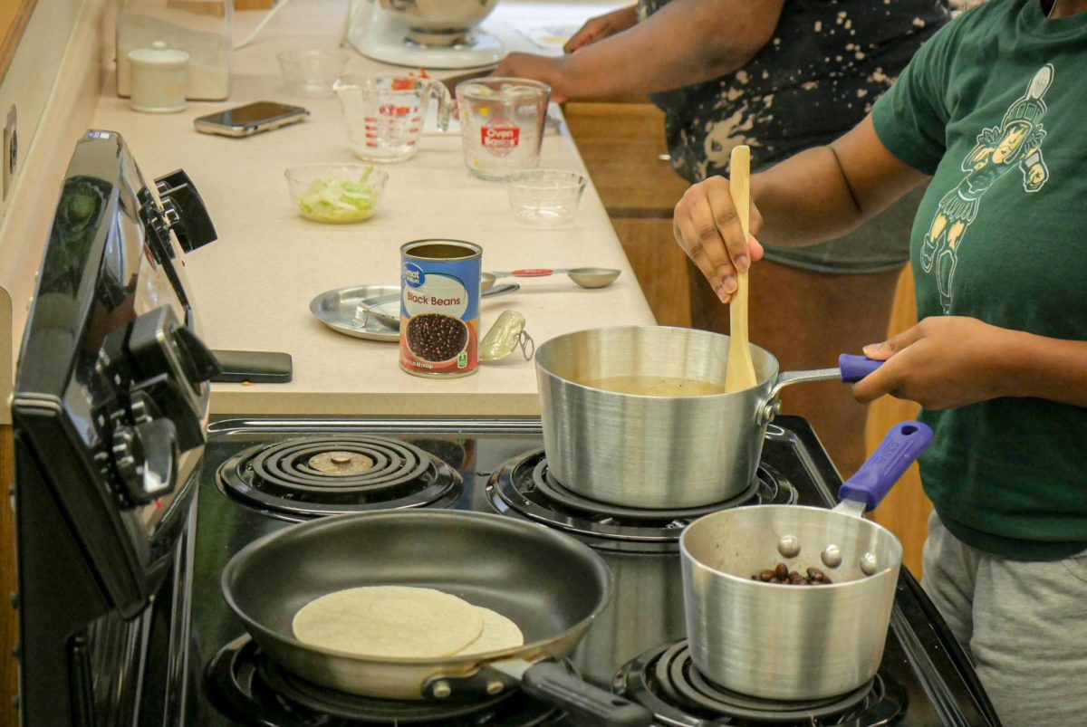 Students start to cook the beans and corn for meatless tacos during a healthy cooking class.
