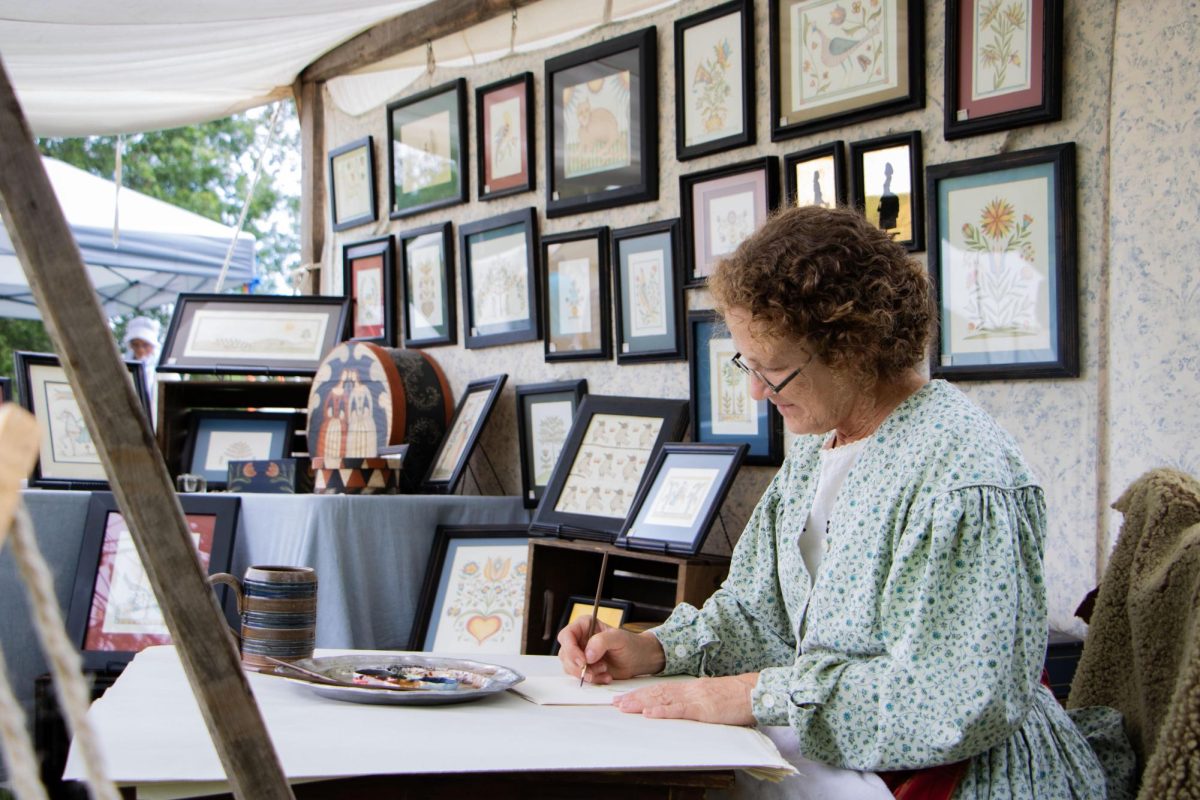 Valerie Skinner, a painter specializing in 18th century watercolors, works on a new painting at Harvest Frolic at the Lincoln Log Cabin State Historic Site.