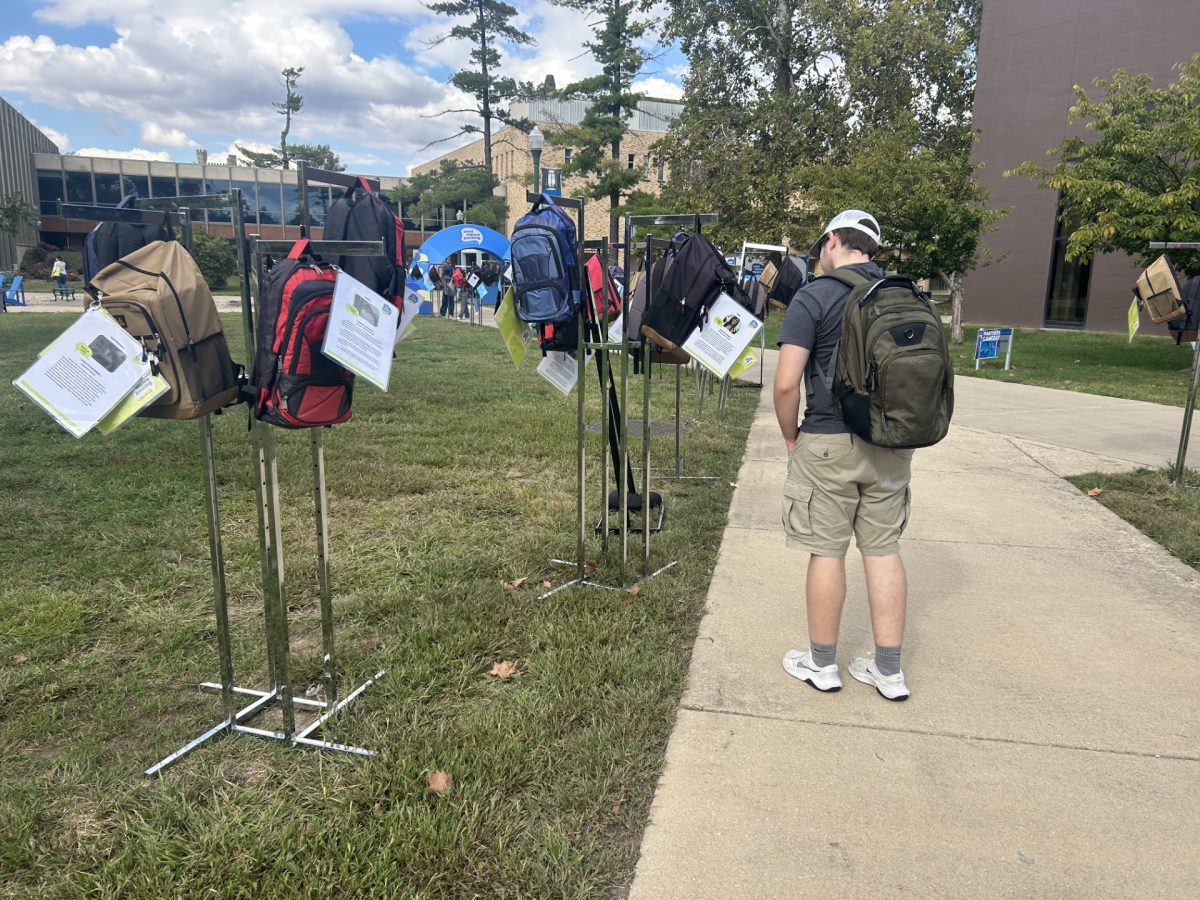 Mark Pointer Jr, a freshman history major, reads a story attached to a backpack at the Send Silence Packing Exhibit in the Library Quad in Charleston, Ill. on Thursday afternoon, Sept. 26.