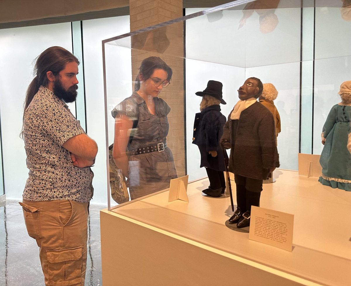 Lily Lawrence, a junior art education major observes the Black History dolls with her plus one Jackson Wooten, in the front room of the Tarble Arts Center at the opening reception 