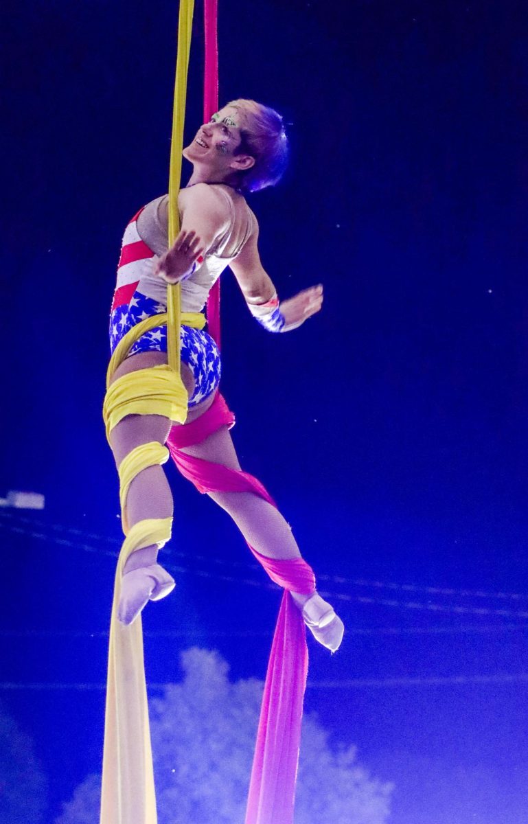 Aerial artist poses in the air while being held up by aerial silk ropes during the All-American Circus' performance Saturday.