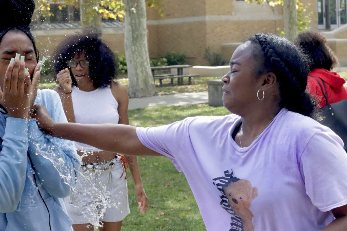 Destinee Patterson, a senior English language arts teacher education major, splashes Shania Lankston, a senior psychology major at the Splash-A-Kat event fundraiser on Sept. 26, 2024 at the Doudna Fine Arts Center overhang