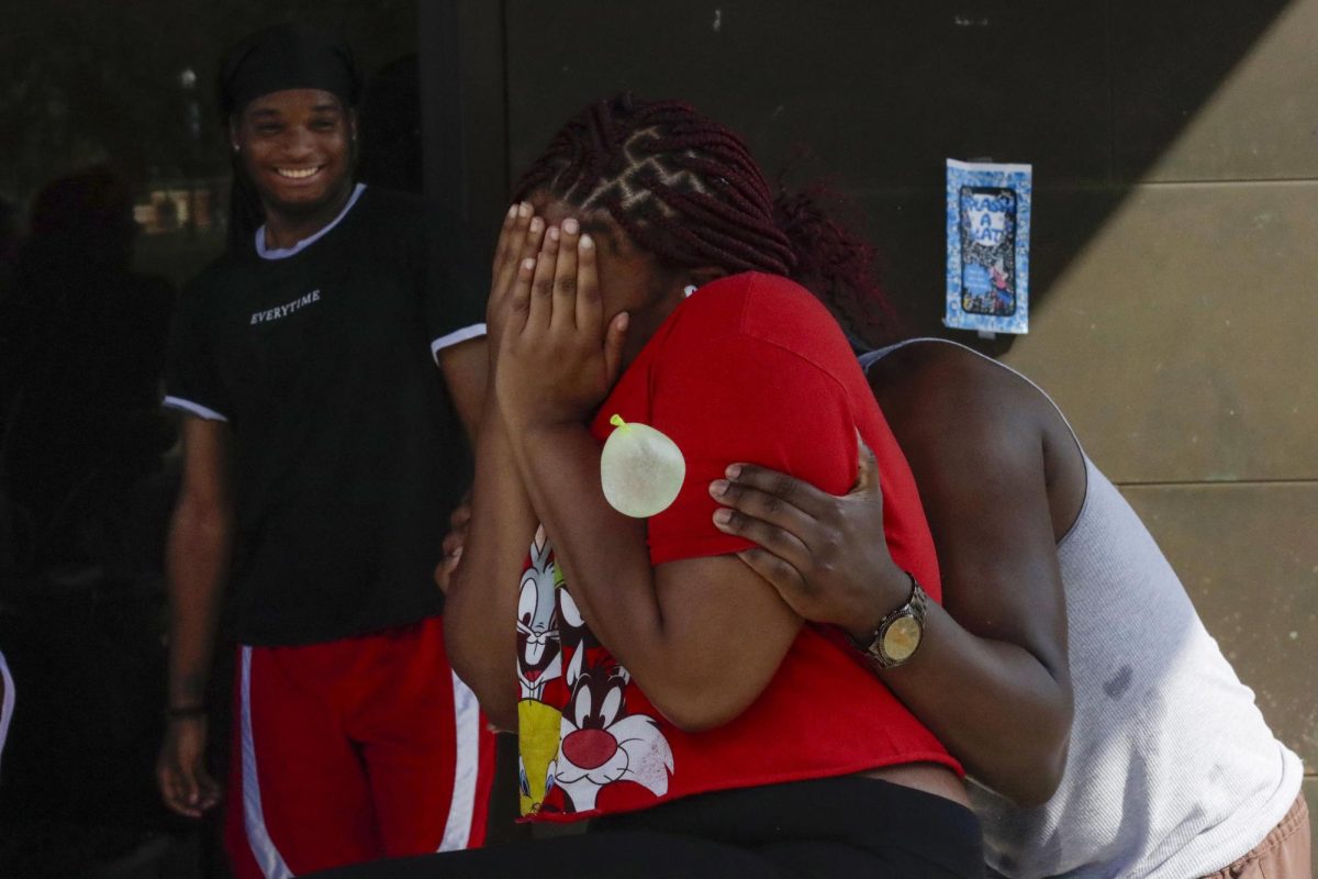 Brea Howard, a senior theatre major, protects her face from a water balloon at the Splash-A-Kat event fundraiser on Sept. 26, 2024 at the Doudna Fine Arts Center overhang 