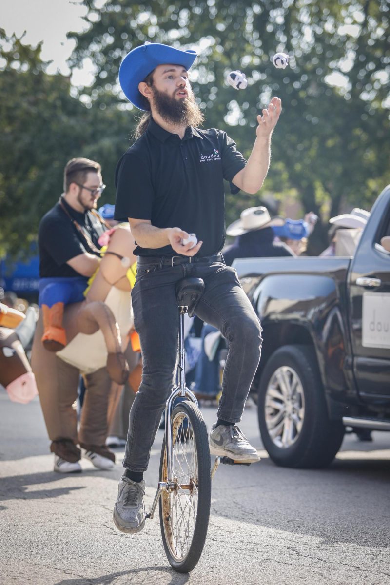 Paul Nau, a graduate music student, juggles on a unicycle during the homecoming parade Saturday morning. 