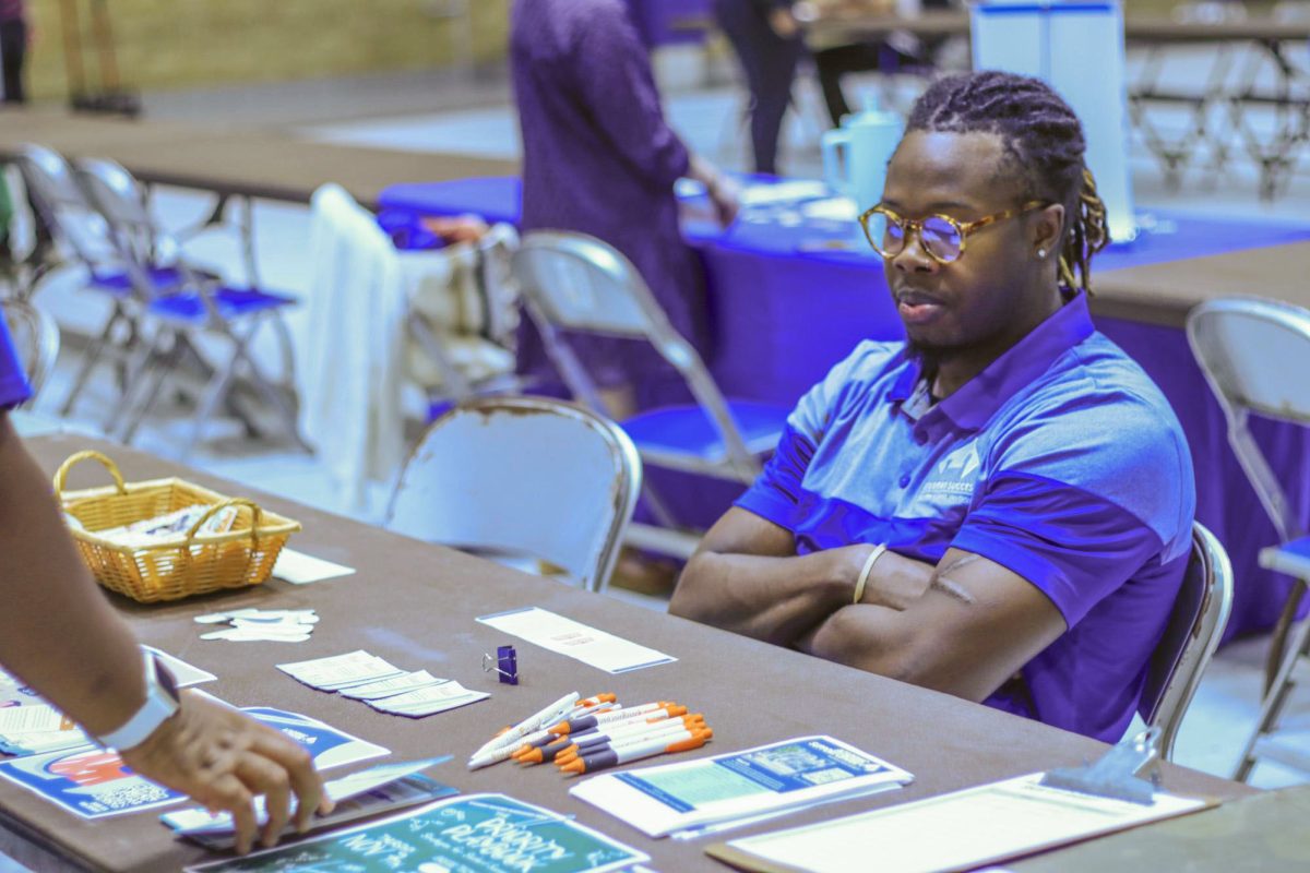  Lesly Nazon, a graduate student in computer technology, informs students about the academic support center at the Health and Wellness fair.