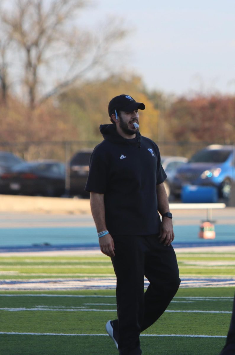 Football strength coach Jacob Hillmann leads a stretch, warmups for the team to get started for the teams practice, 