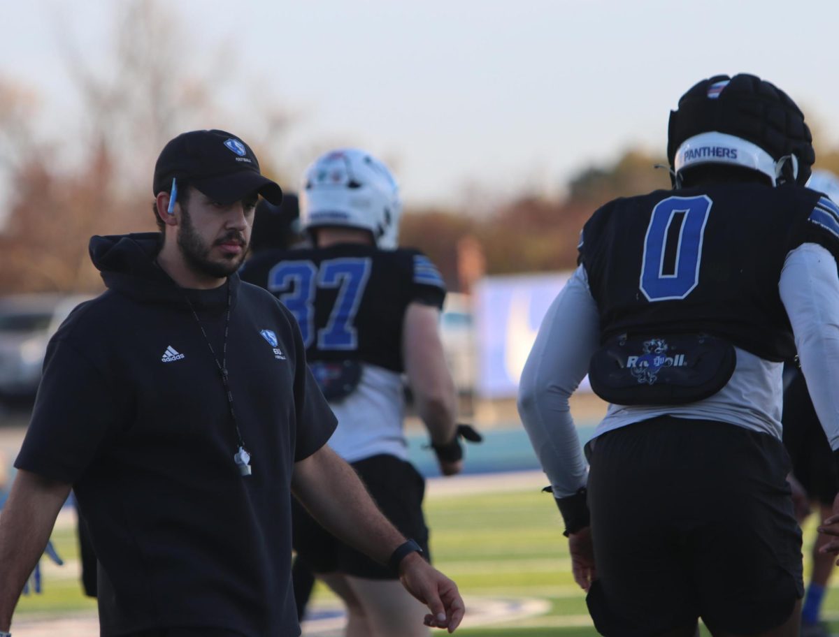 Football strength coach Jacob Hillmann leads a stretch, warmups for the team to get started for the teams practice, 