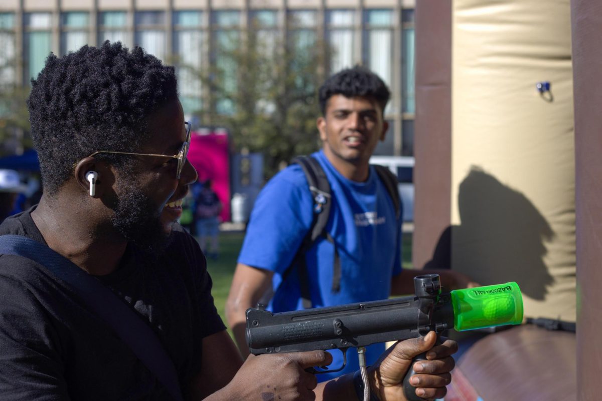 Erik Gordon-Quiacoe (left) a grad student in cyber security and Harshith Gudapureddy (right) a grad student in computer technology both enjoy a casual ball shooting attraction at the Rodeo Round-Up homecoming event in the Library Quad.