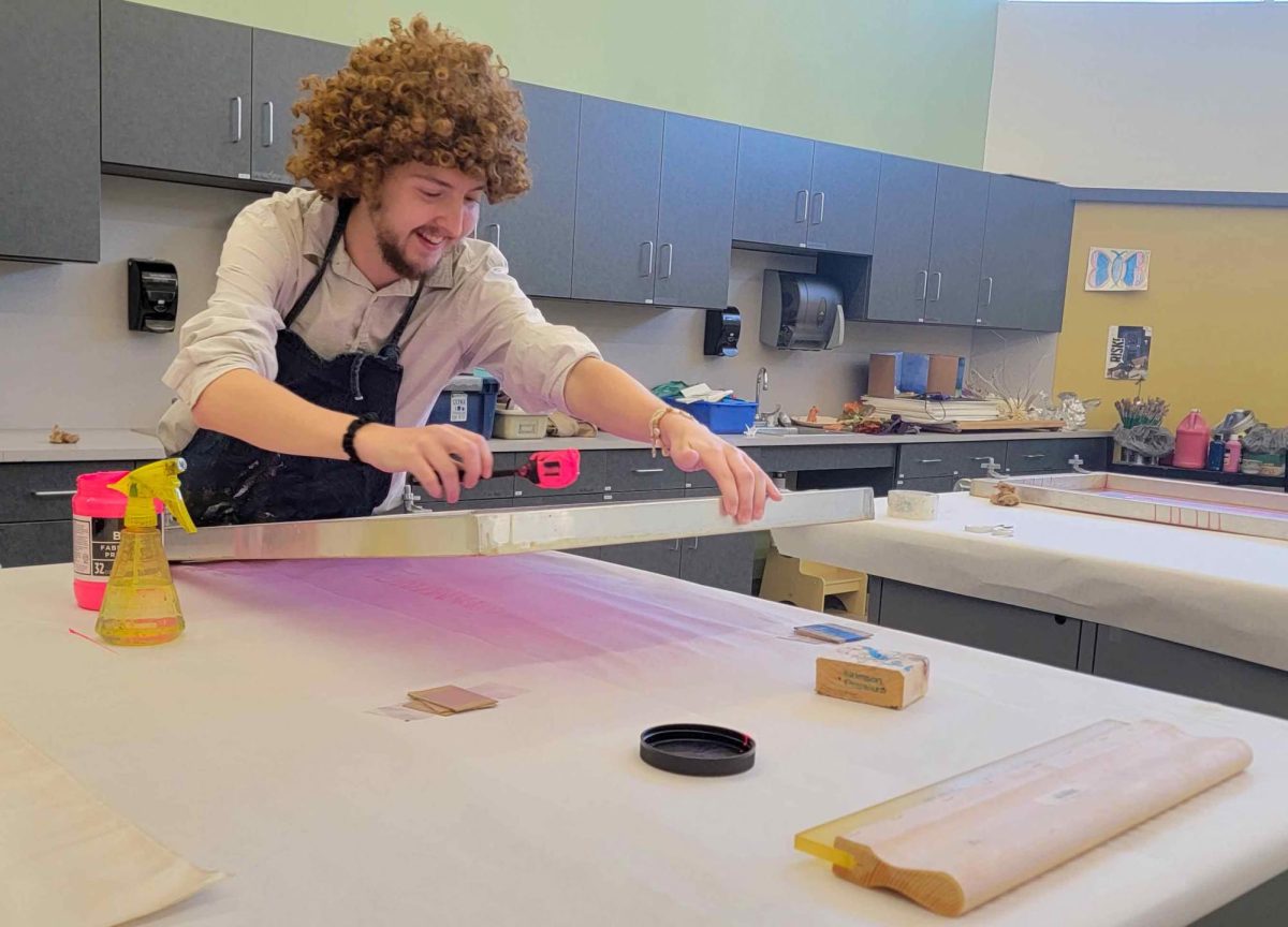 Graduate studio art major Tristen Hahn paints a piece of fabric using a screen printer during the Scream Print event in the Tarble Arts Center on Oct. 18, 2024.