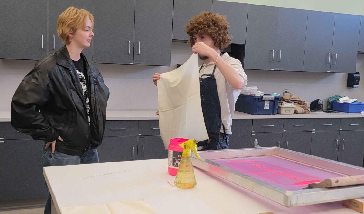 Graduate Student Studio Art major Tristen Hahn talking to Junior Criminology major Joey Dhom about how to screen print a piece of fabric in the Tarble Art Center during the Scream Print event on October 18, 2024.