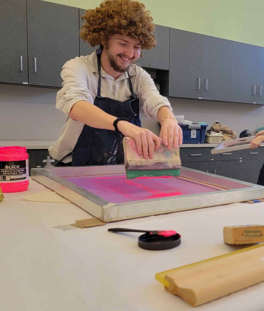 Graduate Student Studio Art major Tristen Hahn painting a piece of fabric using a screen printer during the Scream Print event in the Tarble Art Center on October 18, 2024.