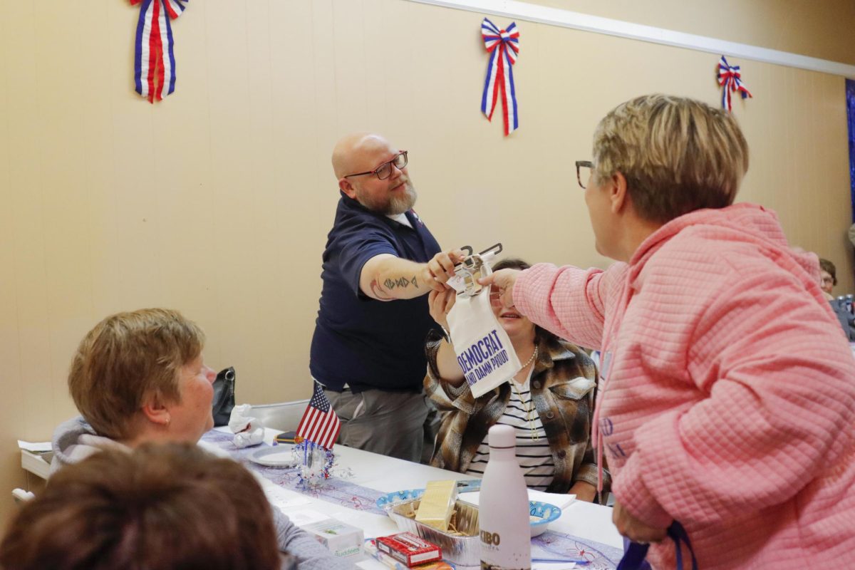 Sue Fuller hands Matt Keller the prize he won during a raffle that was going on through the night at the Coles County Democratic Party headquarters Tuesday.