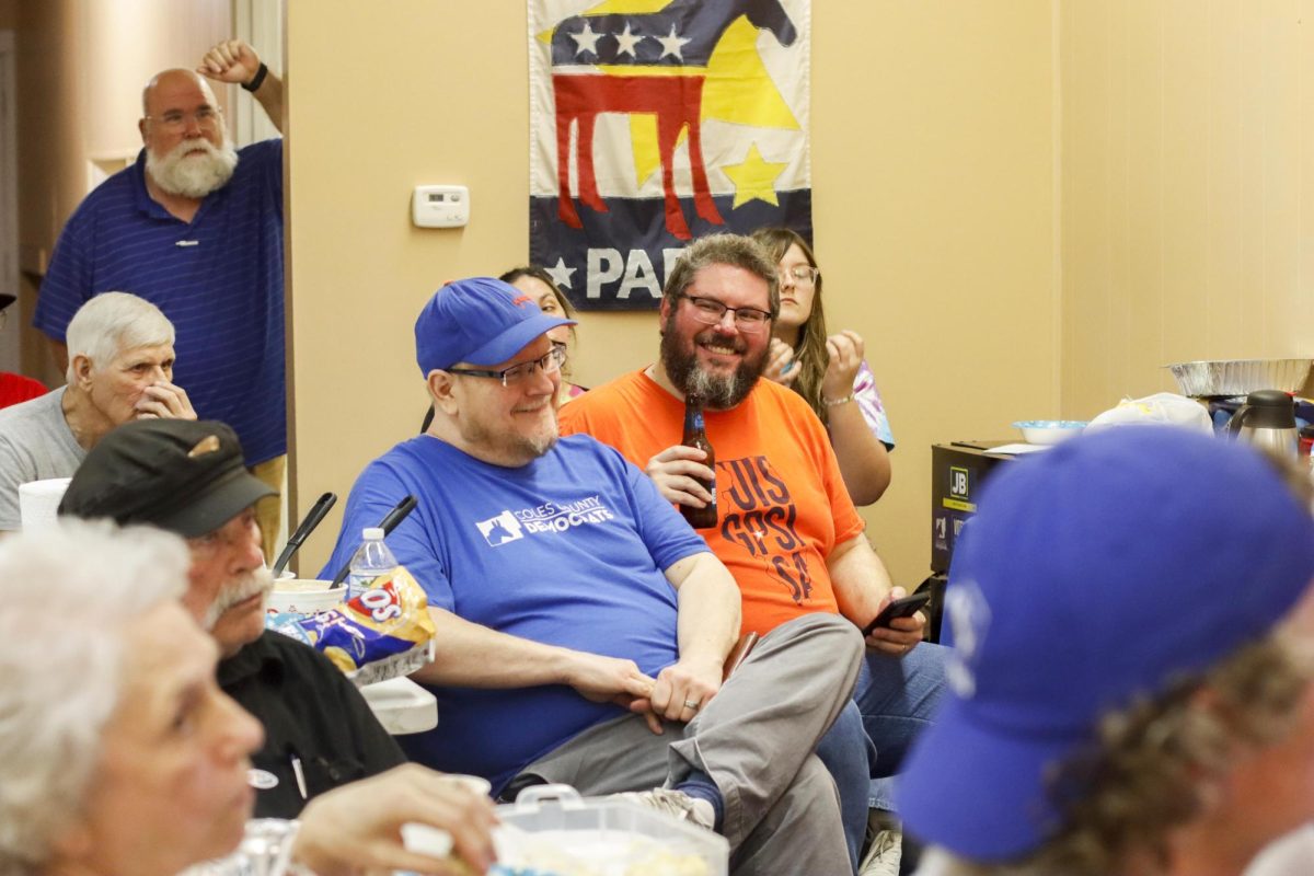 Wesley Allan (in blue) and Matt Titus (in orange) react to a comment made by another person watching the election at the Democratic watch party Tuesday.