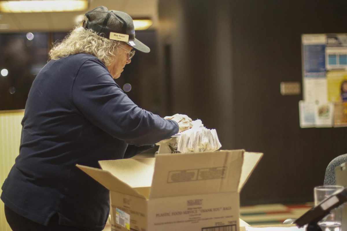 Mary Kaiser restocks the bags at checkout before more students come to check out.