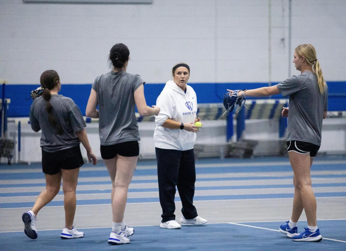 Softball Head Coach Kristi Paulson talks with some of the infielders about a fielding drill while the rest of the team walks over at practice on Tuesday.
