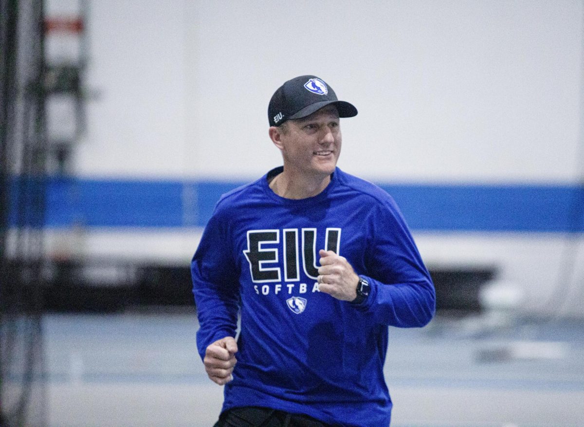 Softball Head Coach Dan Paulson runs through first base during a fielding drill after he hit the ball to the infielders at practice on Tuesday.