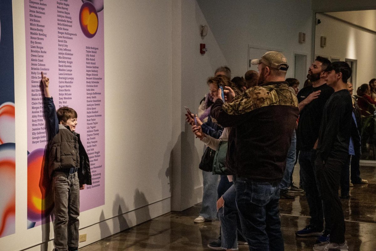 A family shows how proud they are as their child excitedly points to his name on the art exhibit wall in the Tarble Arts Center on Friday.