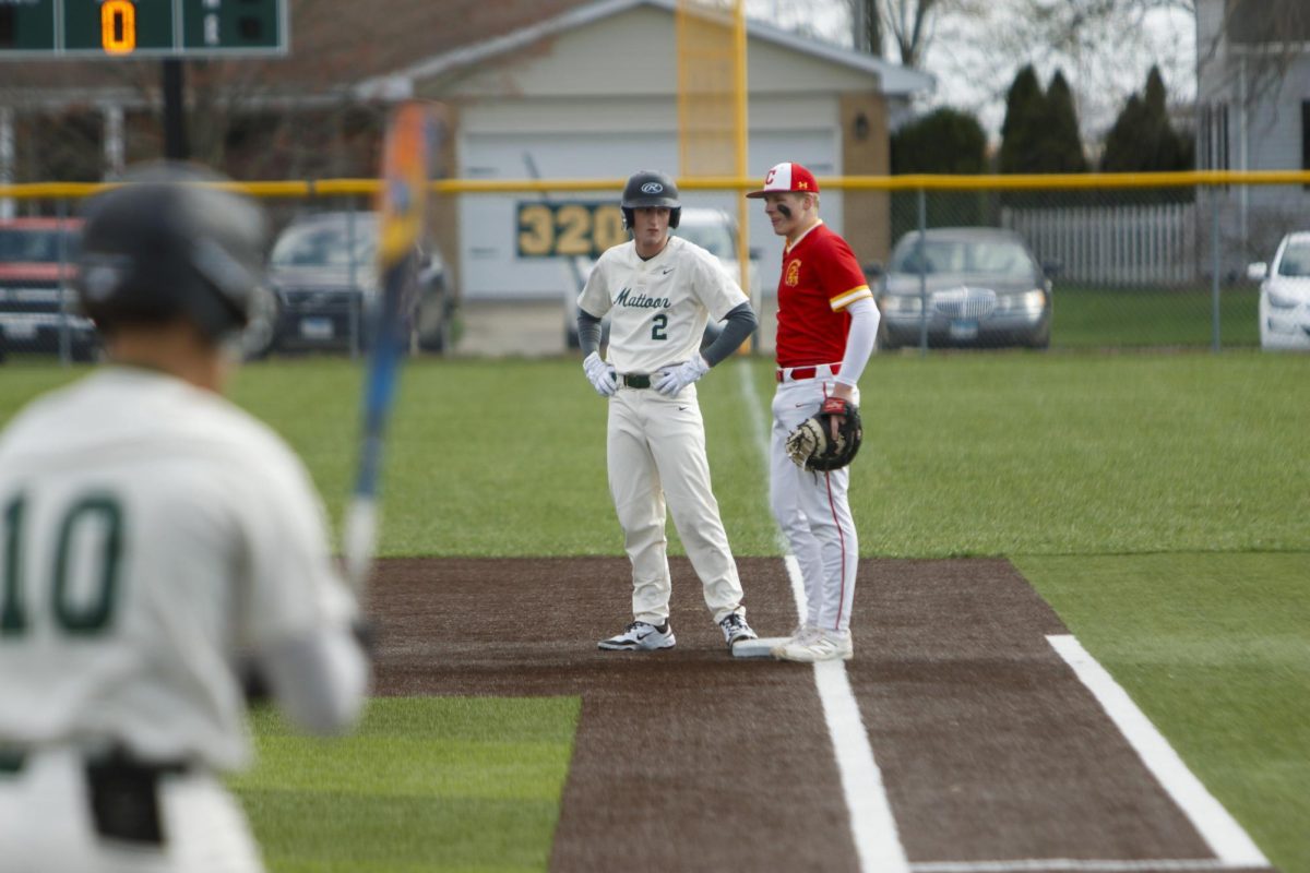 Mattoon High School senior Madden Johnson standing next to Charleston High School sophomore Russel Applegate at first base while Mattoon senior Shayden Neff steps into the batter's box during the first game between Mattoon and Charleston as Charleston lost both games 12-8 and 5-4 on Monday April 7.